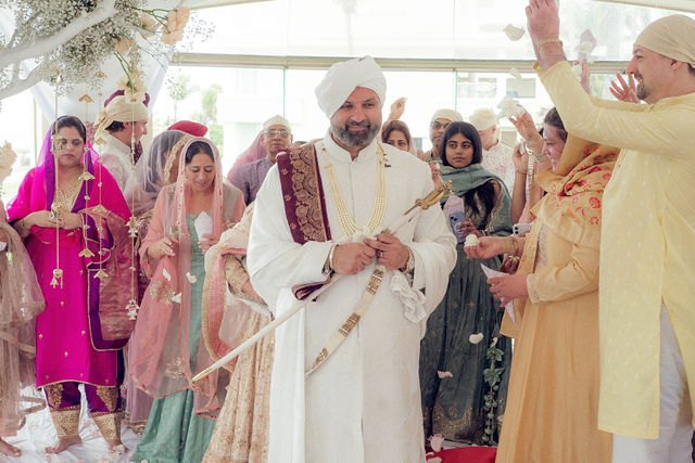 Jiv entering the Anand Karaj with maroon fabric over his shoulder