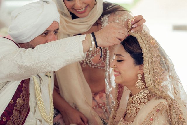A close ceremony moment as an elder adjusts Aisha’s veil