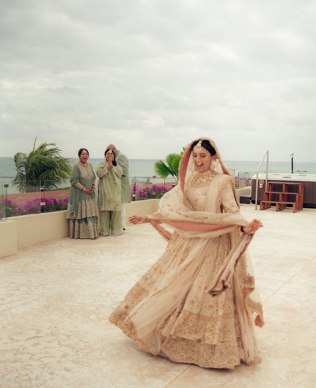 Aisha twirling in her wedding outfit on a terrace near the sea