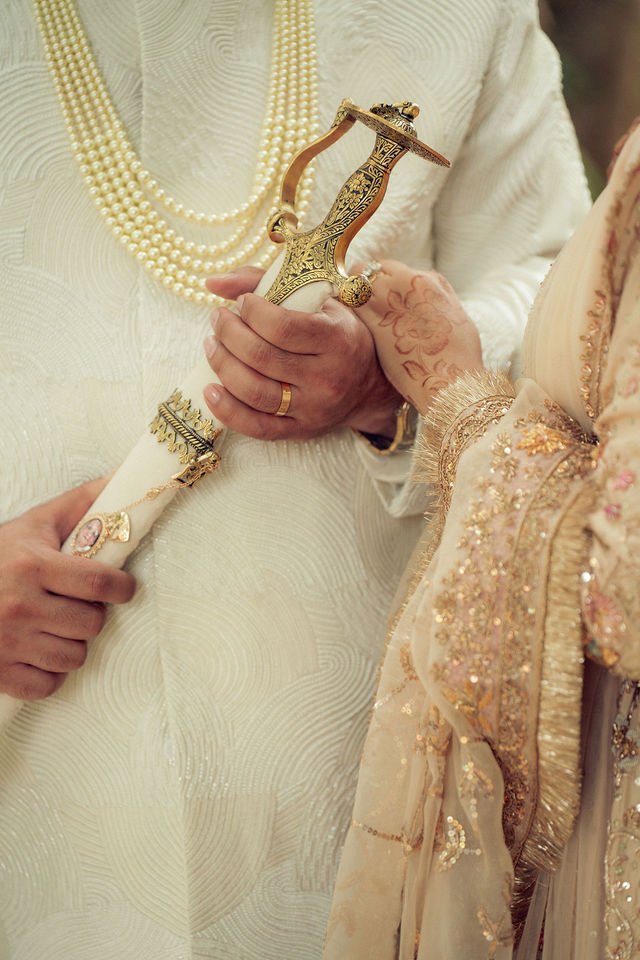 Aisha’s hand near Jiv’s ceremonial sword