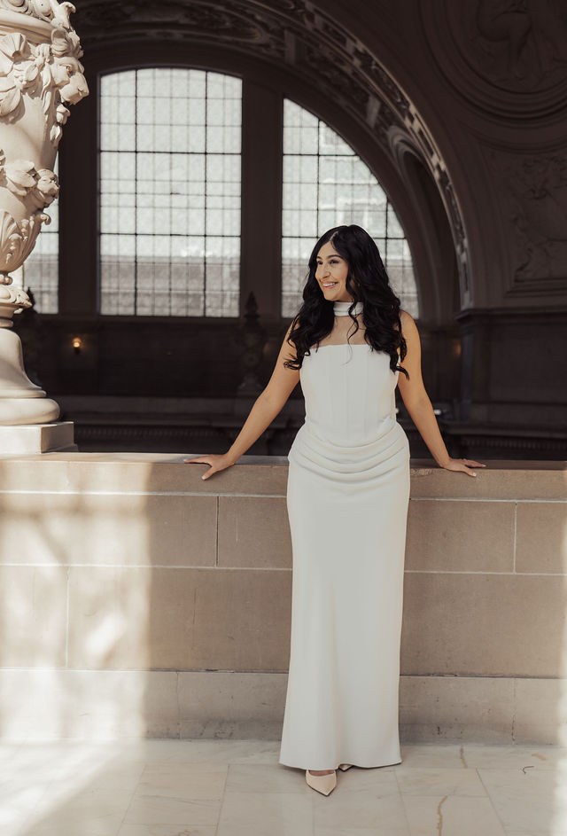 Alisha in a sculptural white dress beneath an arch