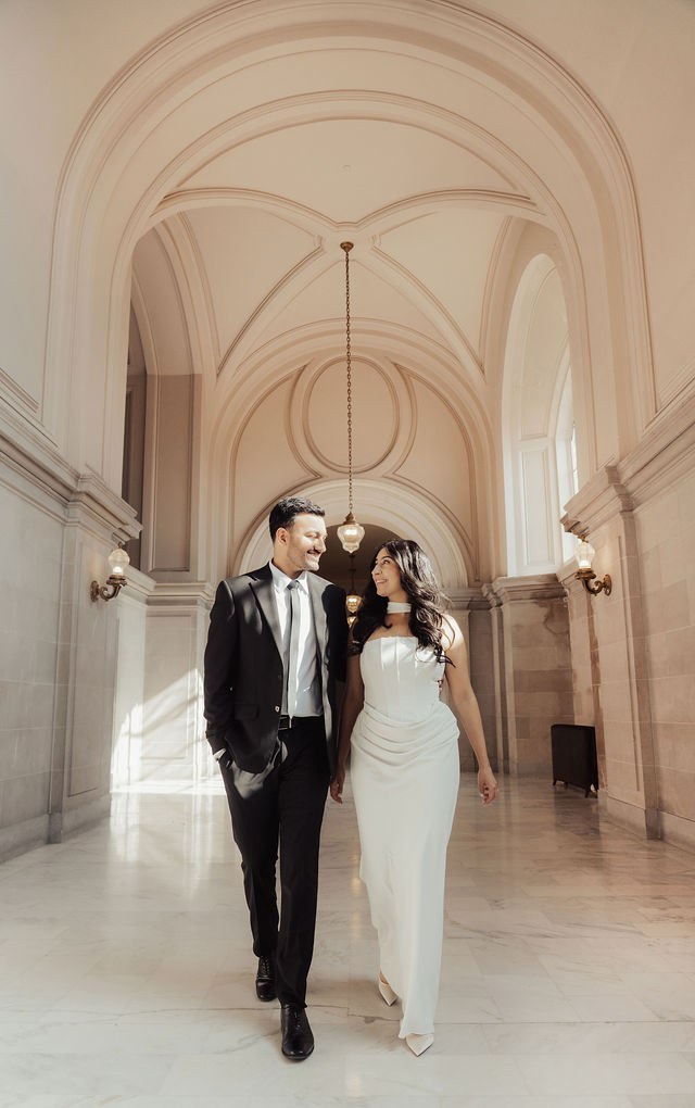 Alisha and Sean walking through a bright vaulted corridor