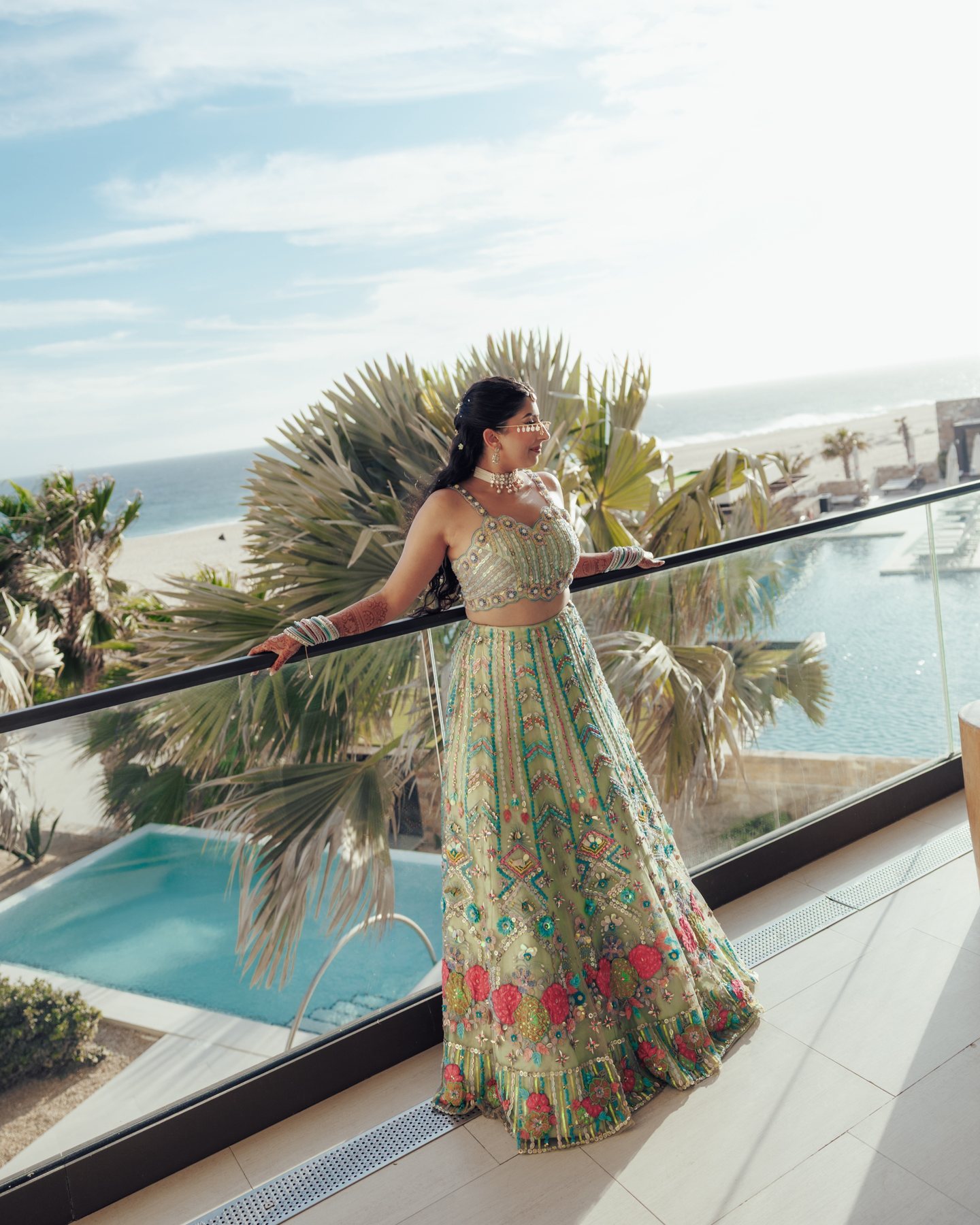 Alisha on a terrace overlooking the sea in a colourful embroidered outfit