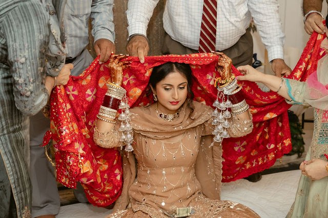 Family placing a red chunni over Banpreet