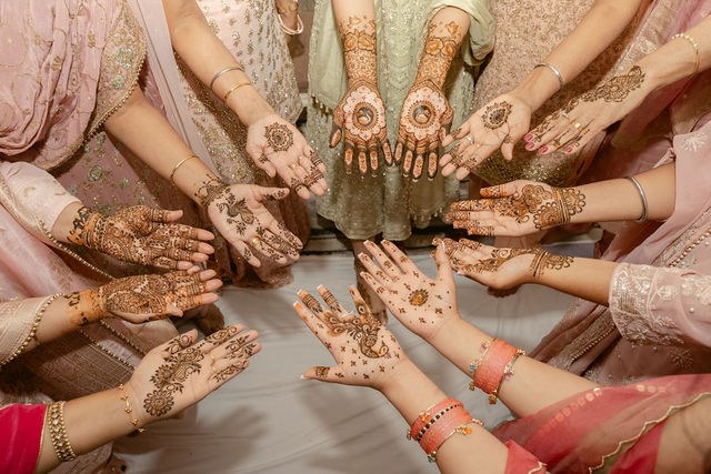 Family hands gather to show their fresh henna