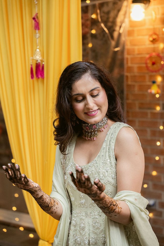 Banpreet admiring her detailed henna beside warm lights