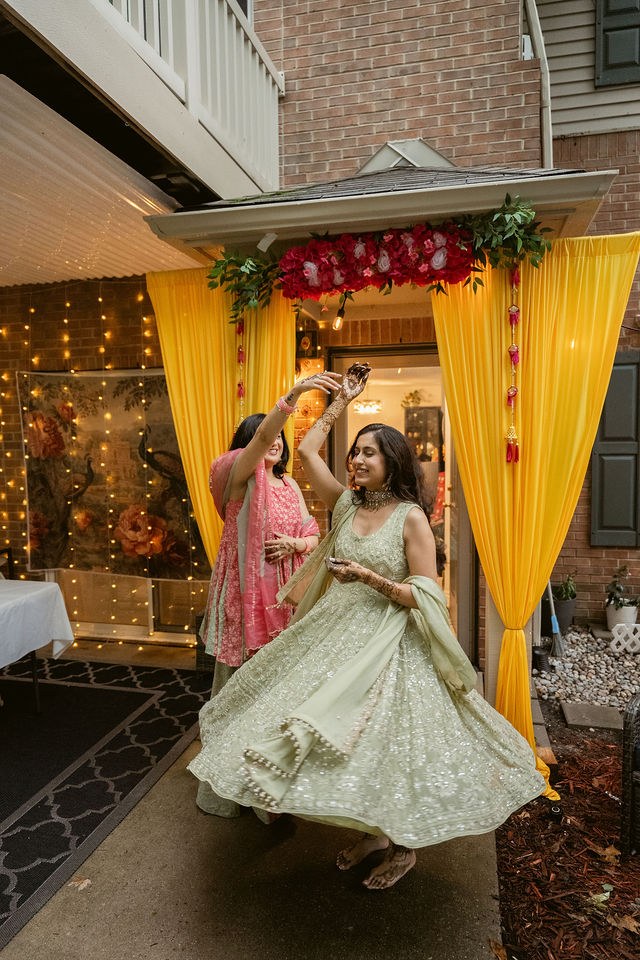 Banpreet twirling with family beneath the yellow Mehndi drapery