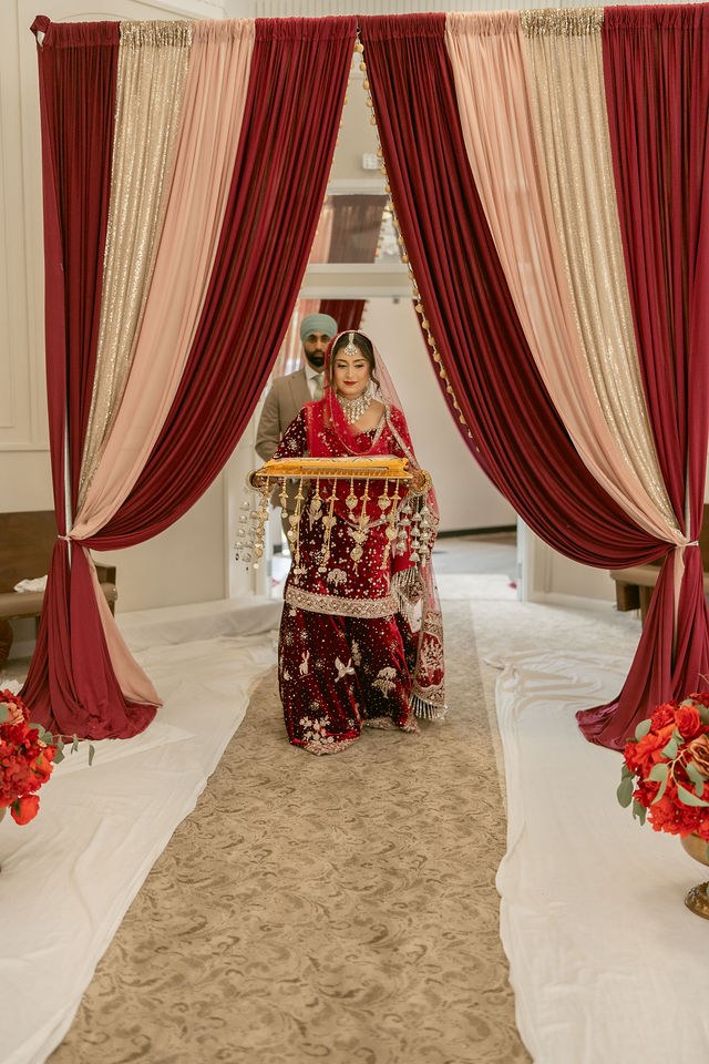 Banpreet framed by red drapery before the ceremony