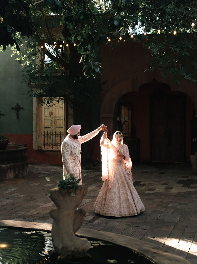 Jessey and Aman holding hands in a garden courtyard