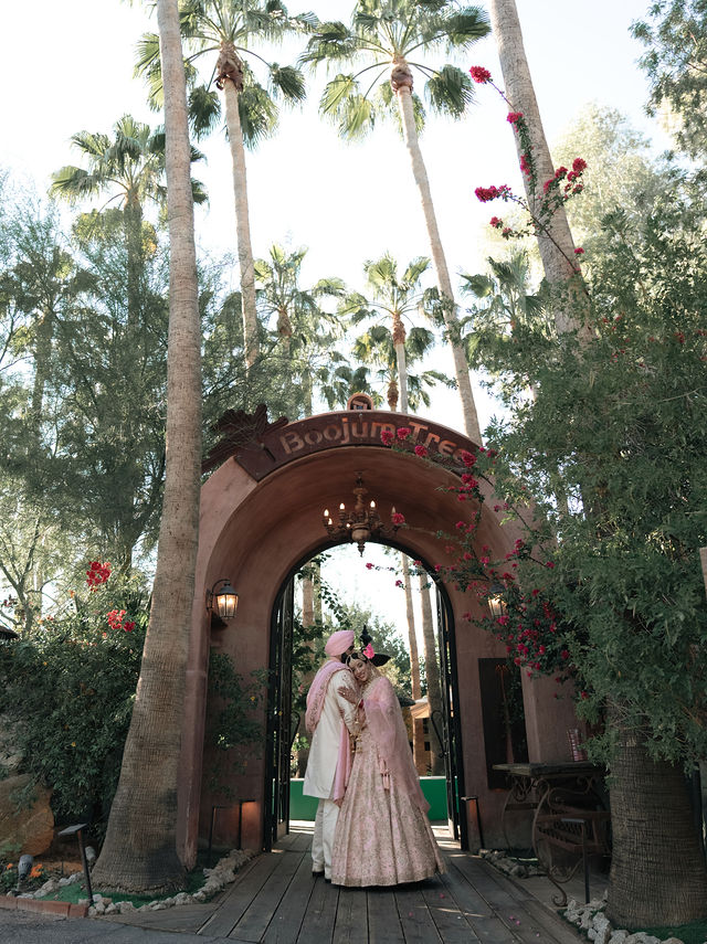 Jessey and Aman framed by an arch and tall palms