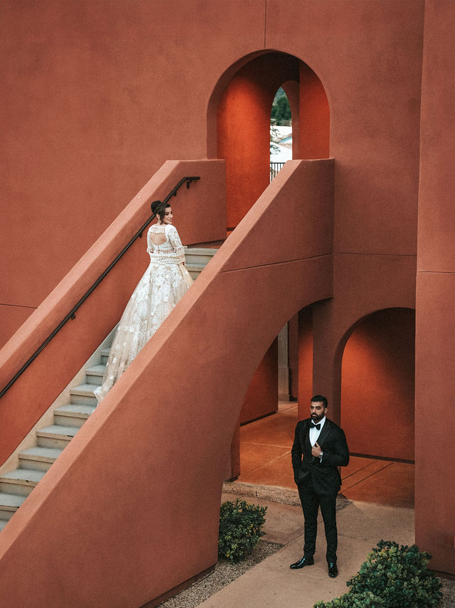 Jessey and Aman in evening attire on a terracotta staircase