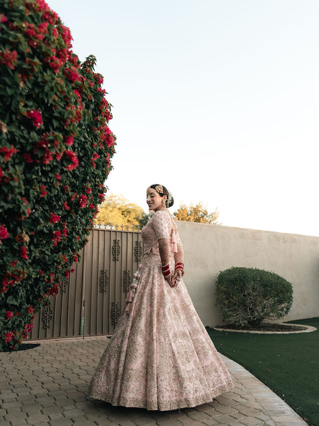 Aman’s pale pink bridal skirt beside a flowering wall