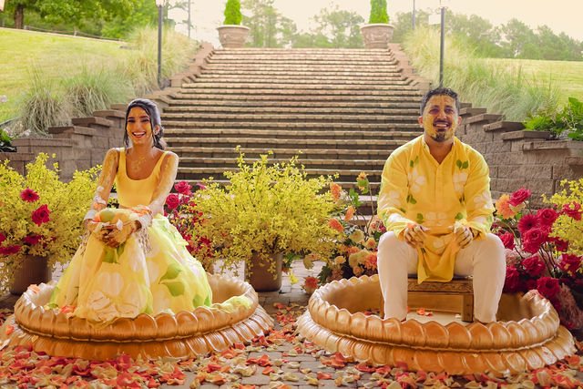 Khyati and Bishal seated amid yellow flowers at their Haldi