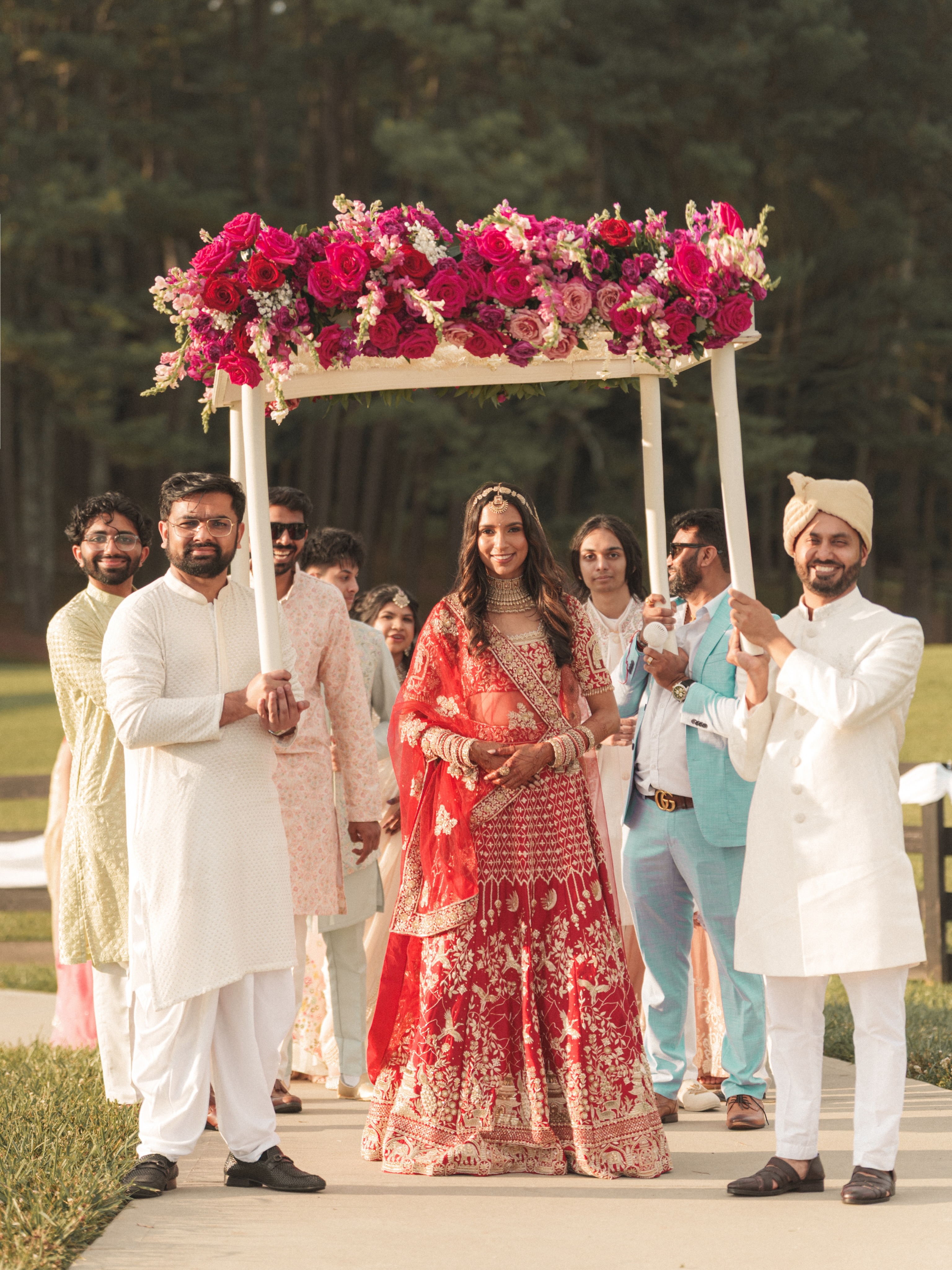 Khyati walking into the wedding beneath a flower canopy