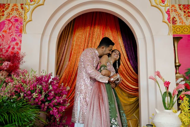 Khyati and Bishal together beneath the colourful Mehndi arch