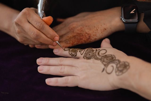 A close view of henna being drawn on a guest’s hand