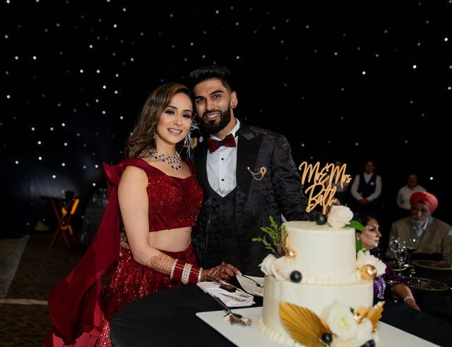 Grace and Karan together beside their wedding cake