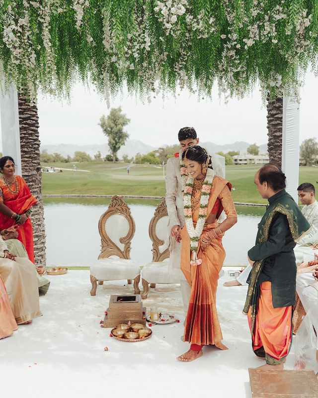 Karishma and Shil at their lakeside ceremony beneath hanging greenery