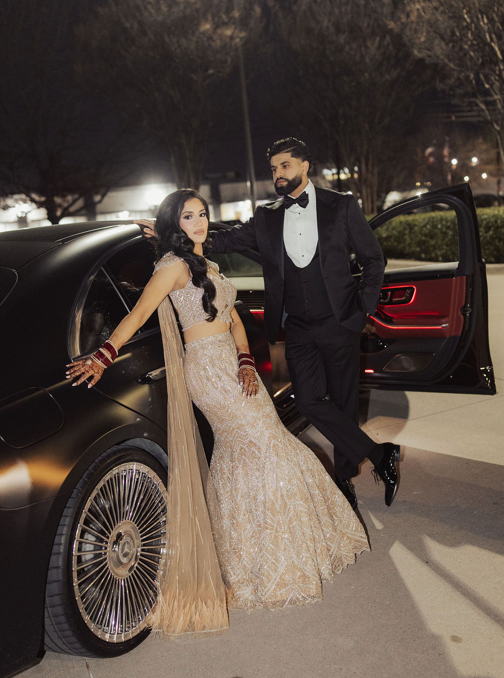 The couple together beside a car in their reception attire at night