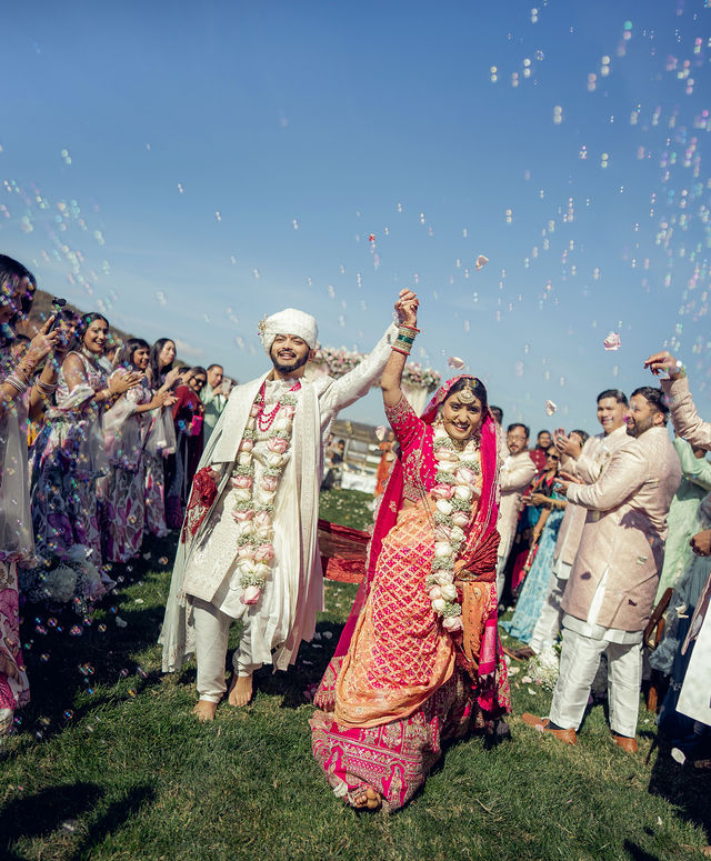 Monali and Sunny walking through confetti after the ceremony