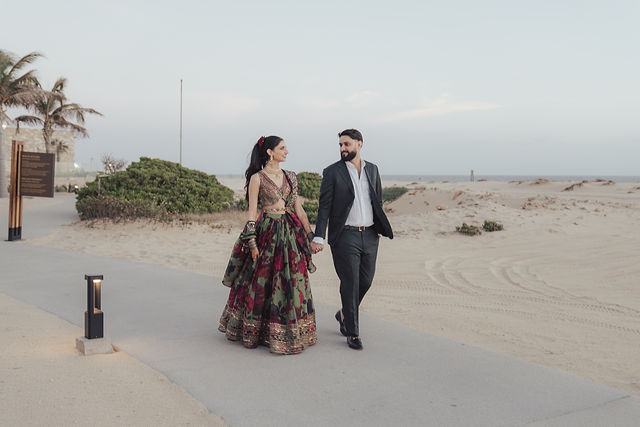 Paul and Gureet walking together across the sand in evening attire