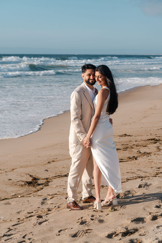 Paul and Gureet embrace beside the ocean