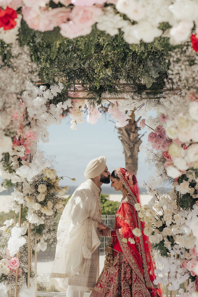 Paul and Gureet beneath a canopy of flowers during their Sikh wedding