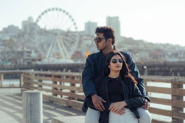 Rachana and Anoop together on the waterfront with a ferris wheel in the distance