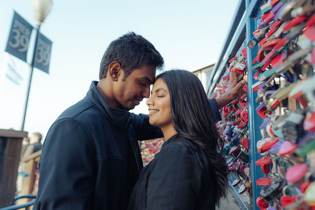 Rachana and Anoop in a close portrait beside a bridge covered in love locks