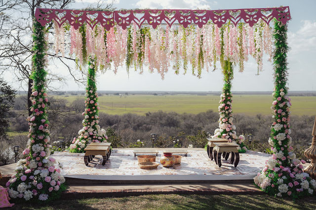The flower-framed outdoor mandap set against the Texas landscape