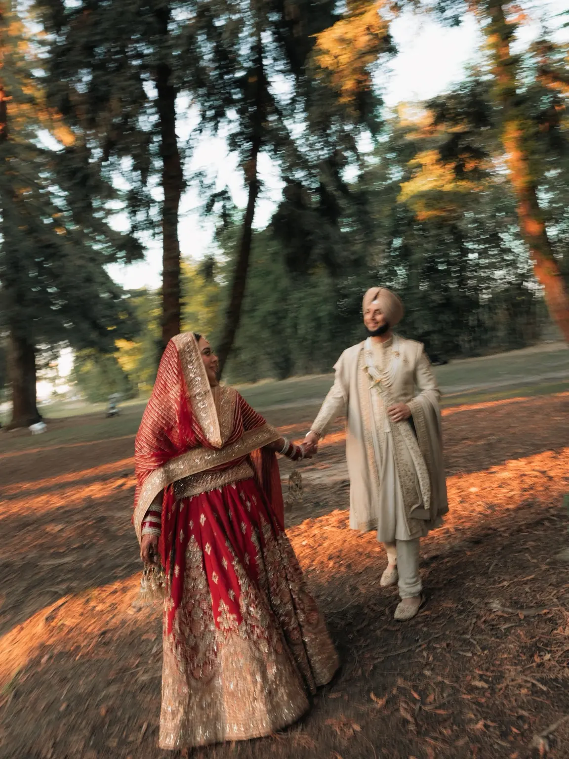 The newlyweds hold hands beneath the trees at Woodward Park