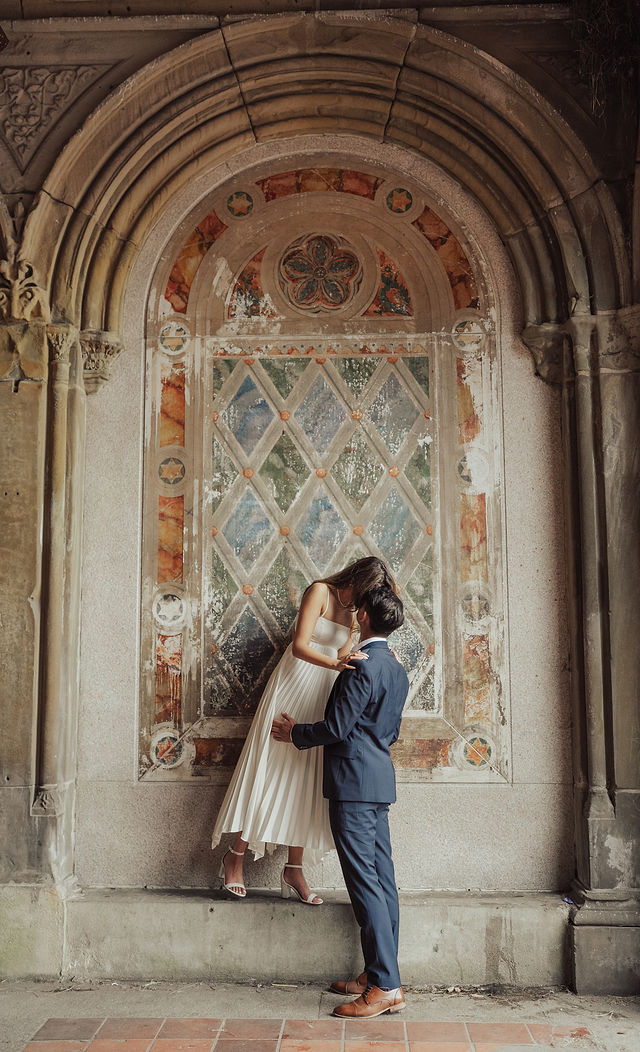 Richa and Shahil standing beneath a richly detailed stone arch