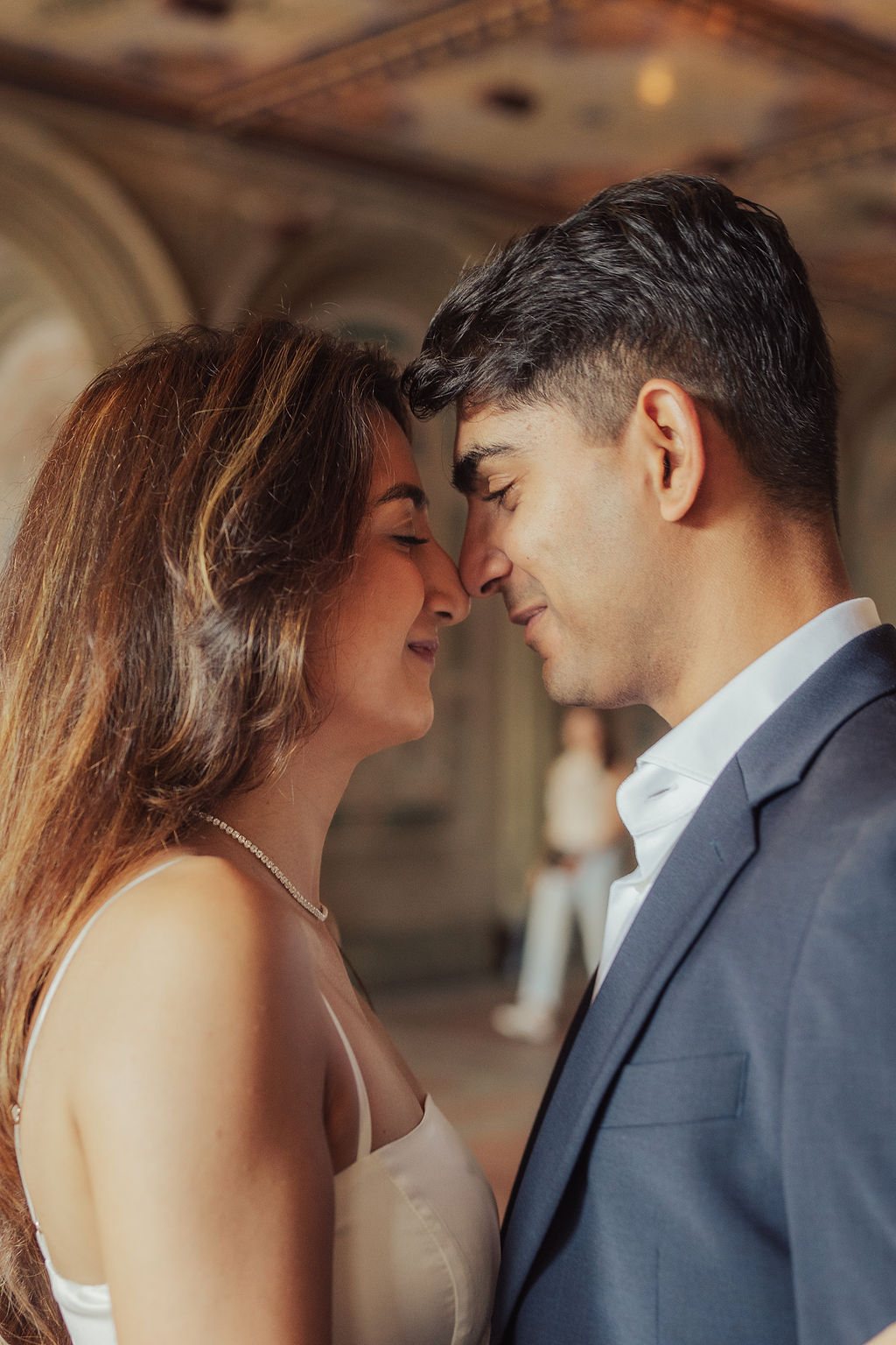 Richa and Shahil leaning close beneath an ornate stone arch