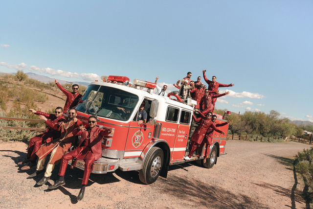 Wedding guests celebrate around a red fire truck in the desert