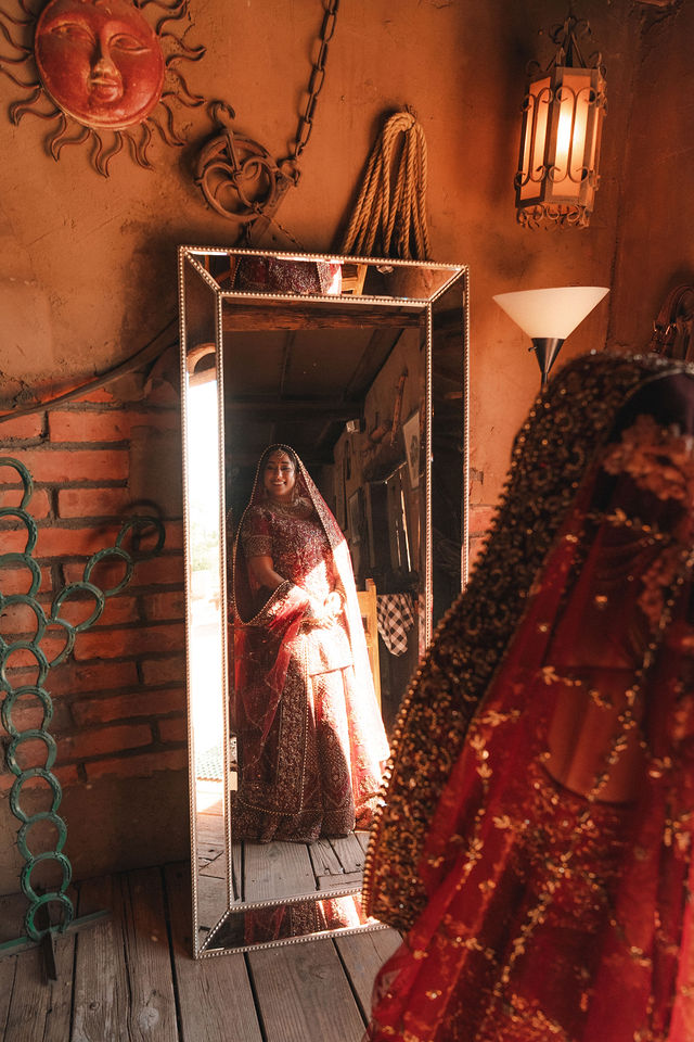 Shachi beside a mirror in warm interior light