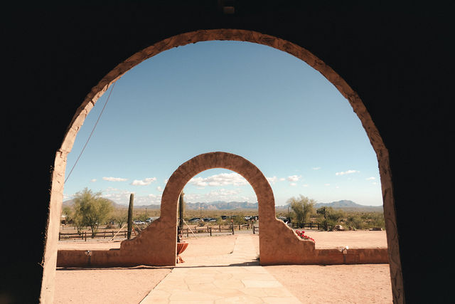 A desert archway frames the distant wedding ceremony space