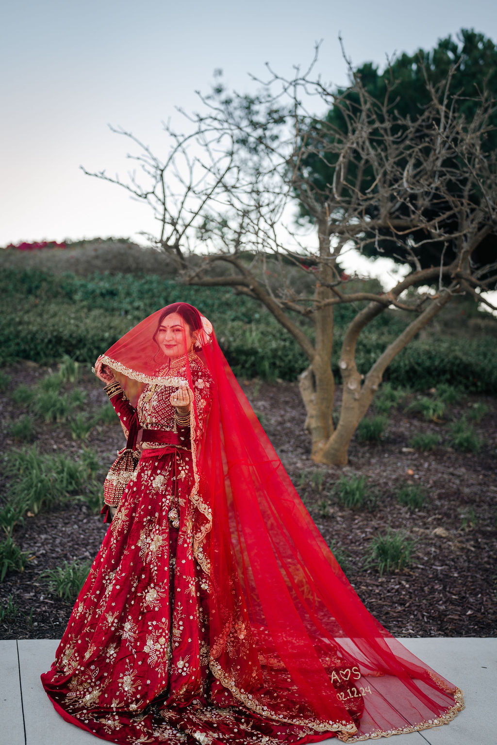 Shayal standing in her red wedding dress and veil