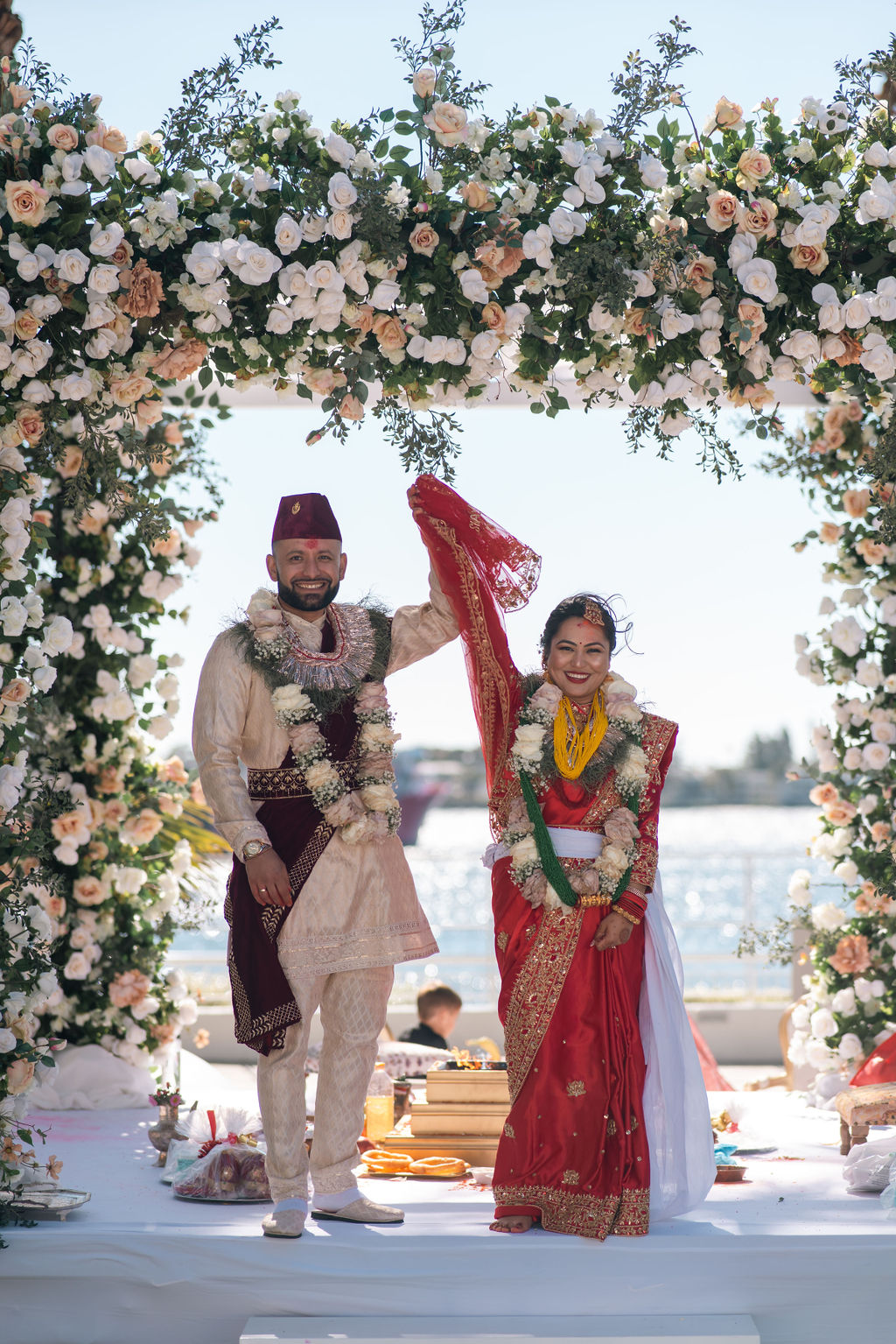 Shayal and Anup beneath a floral wedding arch