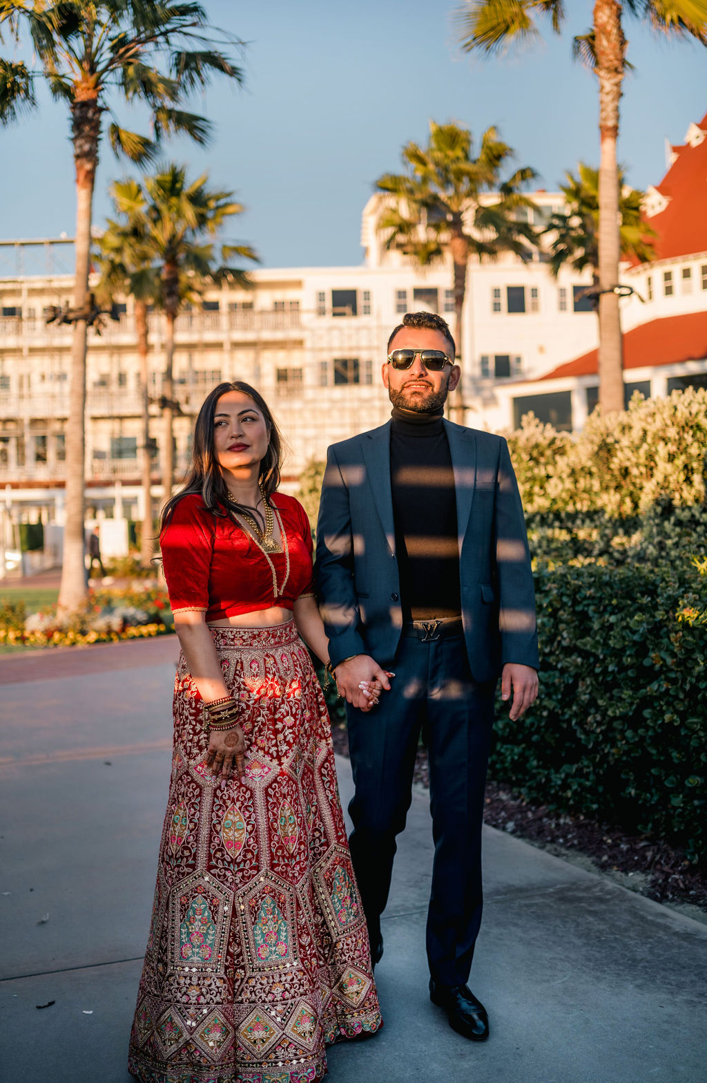 Shayal and Anup walking together beneath palm trees before their wedding