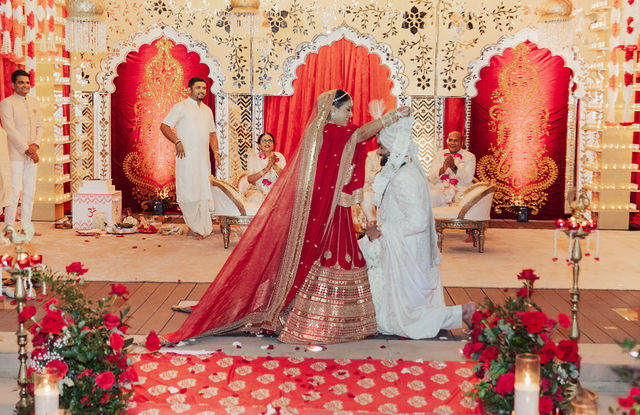 The couple beneath the red-and-gold mandap
