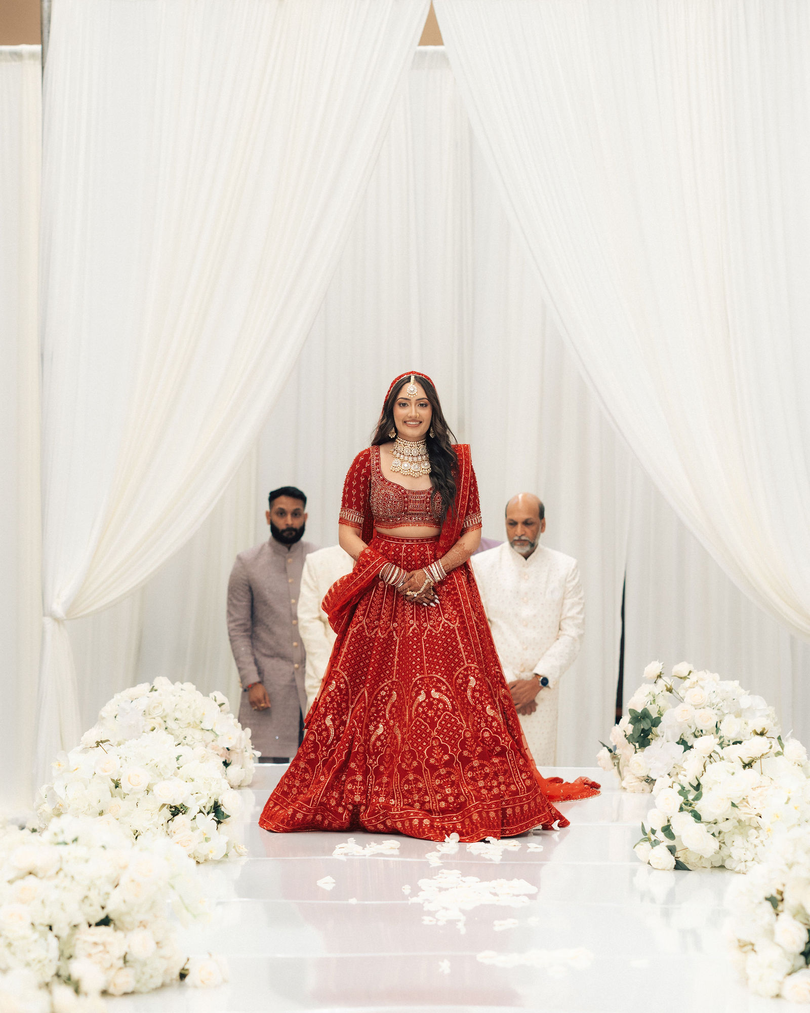 Sonalii standing on the flower-lined wedding aisle