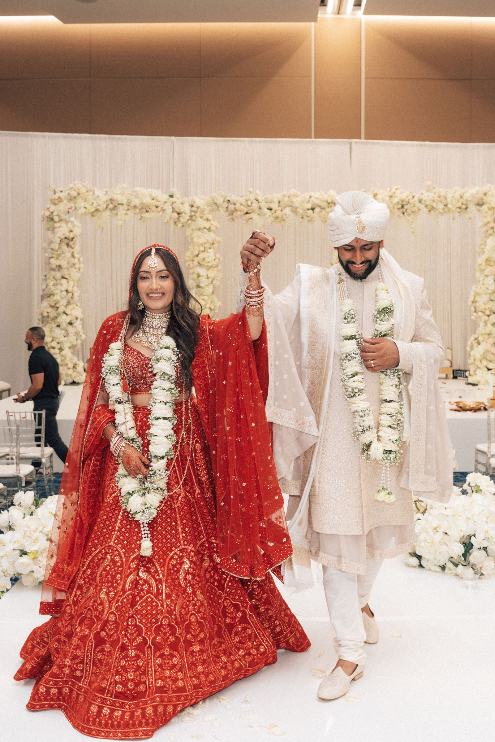 Sonalii and Ravin walking together after their flower-framed ceremony