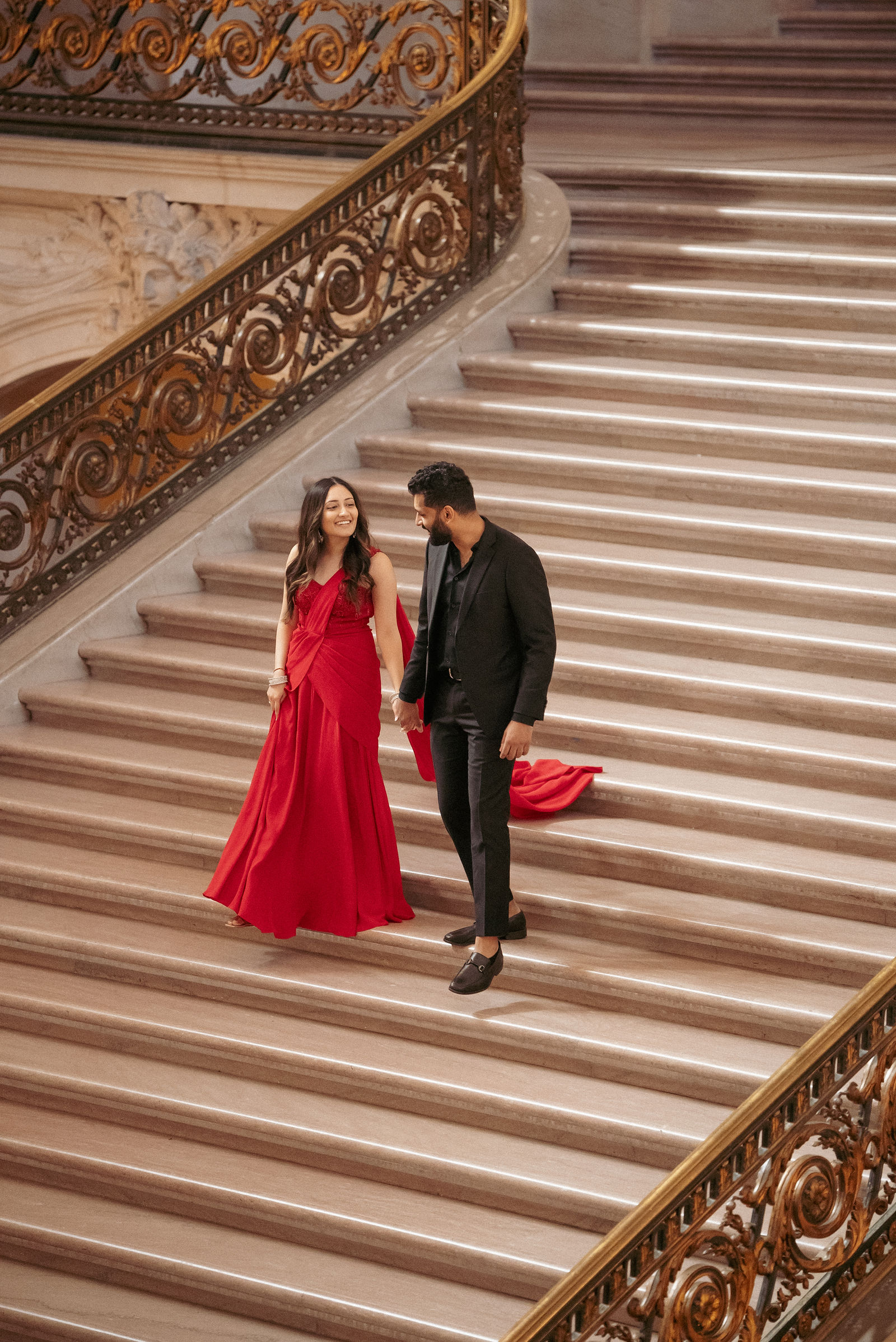 Sonalii and Ravin walking together on an ornate staircase during their pre-wedding session