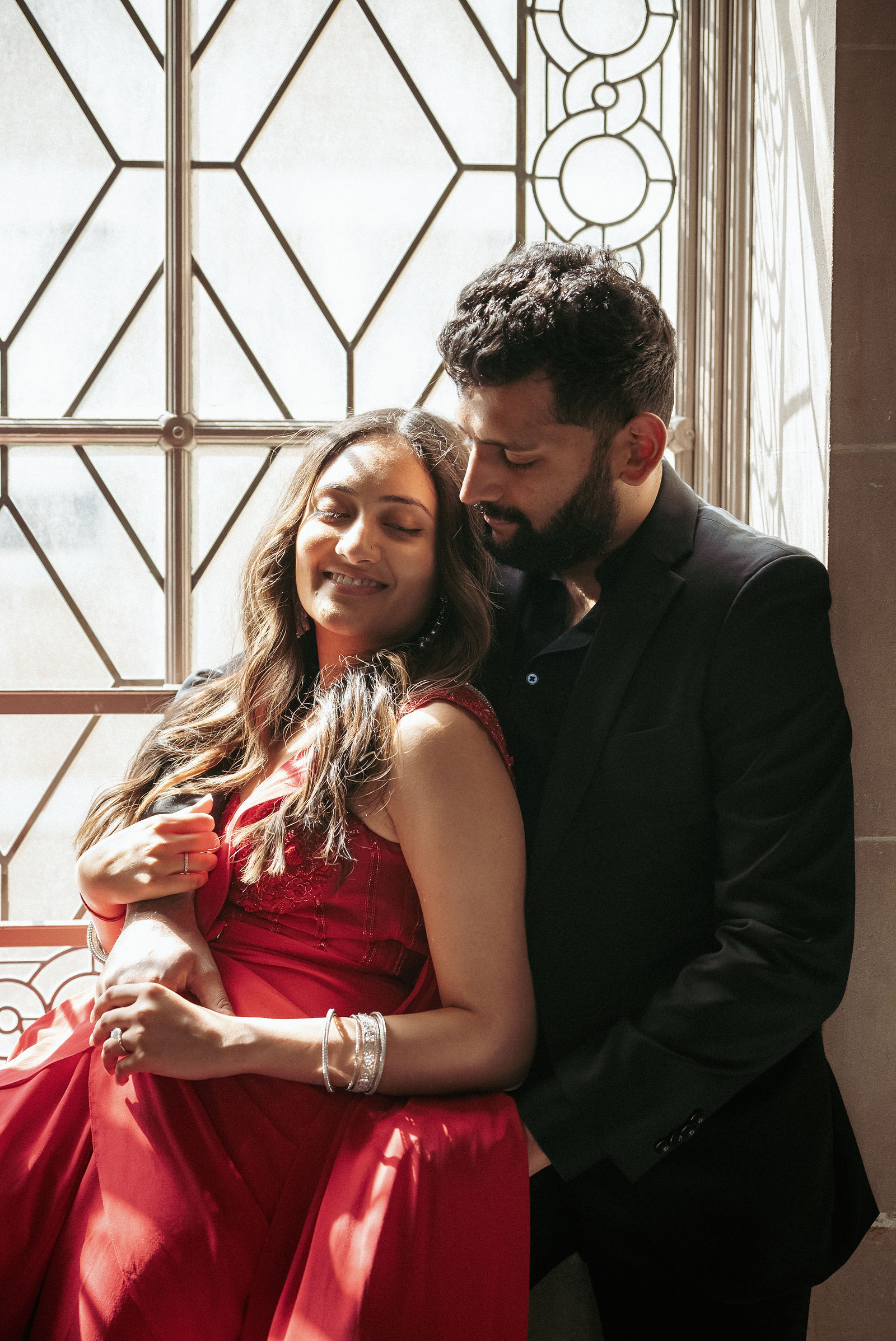 Sonalii and Ravin sharing a sunlit portrait by a patterned window