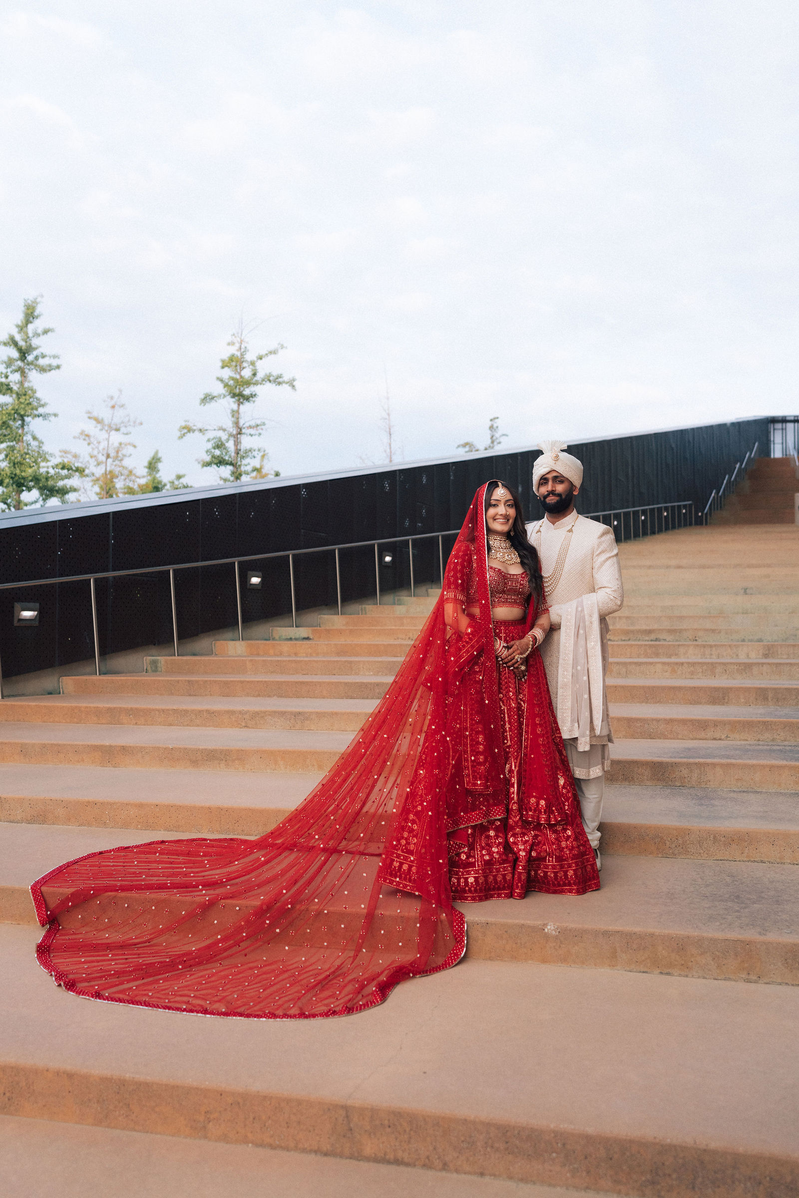 Sonalii and Ravin together on the steps in their wedding attire