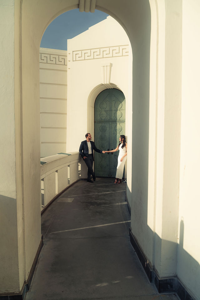 Tanya and Ronit holding hands beneath a sunlit architectural archway