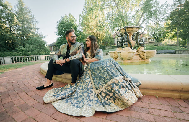 Vidhi and Mayank seated together on the garden's brick path
