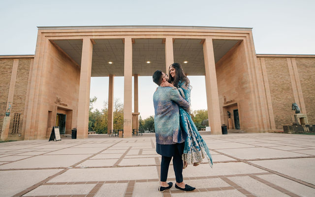 Vidhi and Mayank beneath a wide stone portico