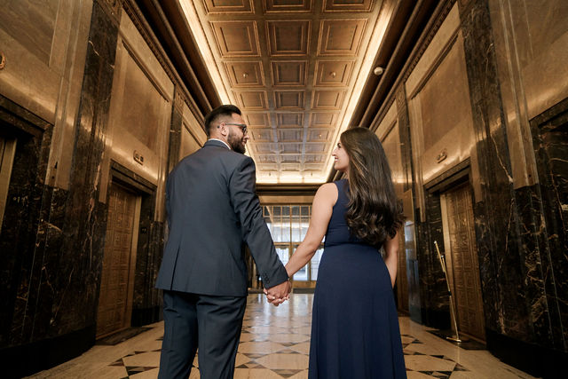 Vidhi and Mayank walking hand in hand through an ornate hallway