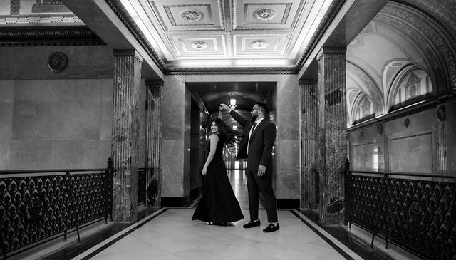 A black and white portrait of Vidhi and Mayank in a long interior corridor